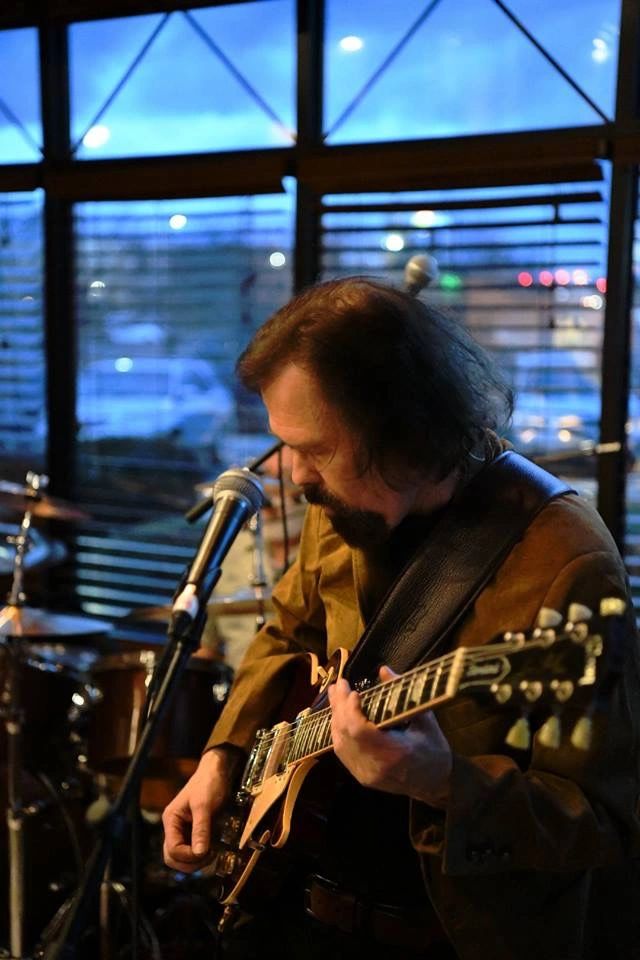 Rob Otis playing electric guitar on stage in the evening light — from his own archive.